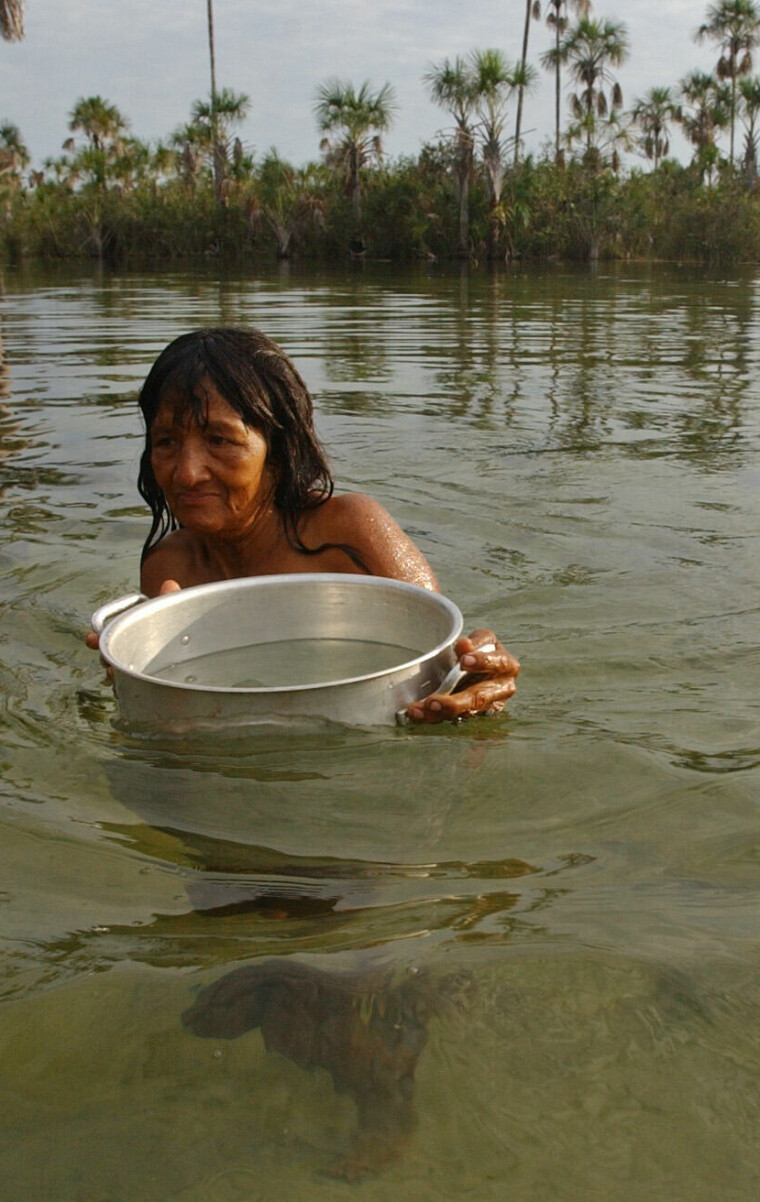 An elder Indian woman of the Suya ethnic group uses a steel pot to fetch water for cooking from the river near her village, Ngojhwere at the border of Xingu Indian Reservation in the northern state of Mato Grosso, Brazil, Nov. 27, 2003. The Xingu is Brazil's oldest and arguably most successful Indian reservation a 6.92 million acre stretch of pristine rainforest where 14 Indian tribes live in much the same way as they have for thousands of years. (AP Photo/Dado Galdieri)
