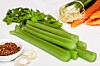 Celery stalks with carrots, parsley, garlic, and seasoning on a white background.