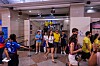 Crowd of soccer fans in jerseys walks through a station concourse toward a train entrance.
