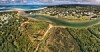 Aerial coastal landscape with an inlet, seaside homes, beaches and forested dunes.